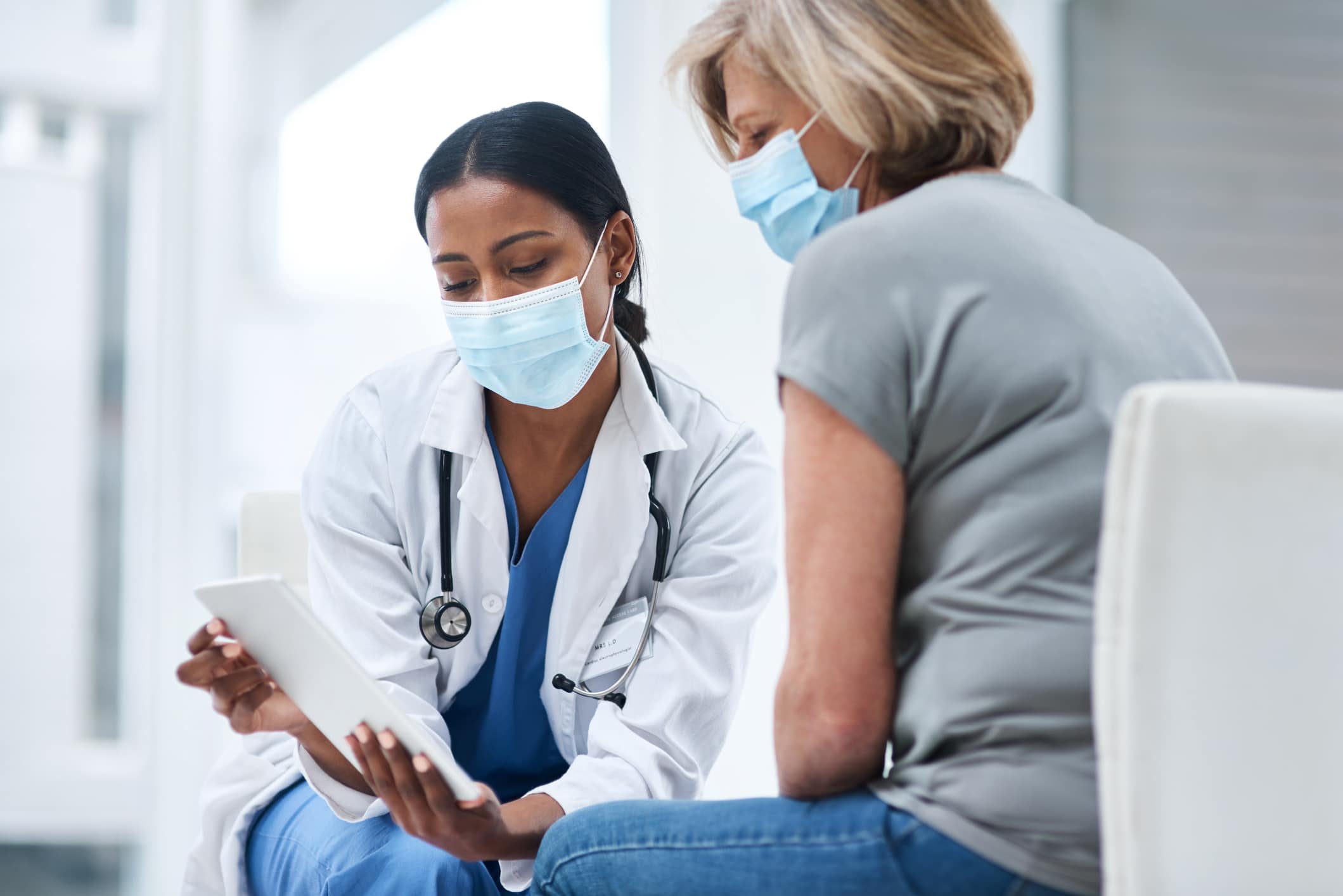 masked doctor talking to masked patient